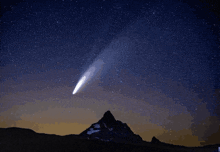 a comet is flying through a starry night sky over a mountain