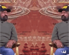 a man with a beard is sitting in a chair in front of a mirror with a red background .