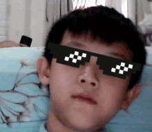 a boy wearing a pair of pixelated sunglasses looks at the camera