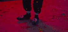 a person wearing a pair of slippers with a donut on them is standing on a pink floor covered in confetti .