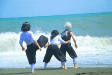 a group of people are standing on a beach .