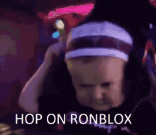 a baby wearing a headband and a hat says hop on ronblox