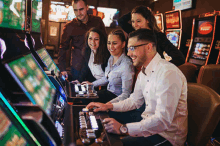 a group of people are playing slot machines in a casino and one of the machines has a red sticker that says ' vegas '