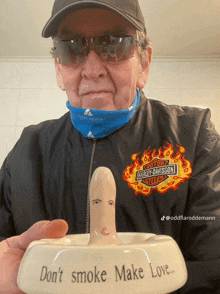 a man wearing a harley davidson jacket holds an ash tray