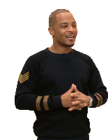 a man in a black sweater with gold stripes on the sleeves is smiling