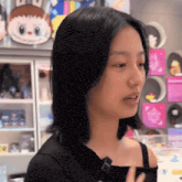 a woman in a black tank top is standing in front of a display of toys