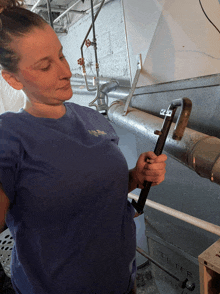 a woman in a blue shirt holds a tool in front of a tilter