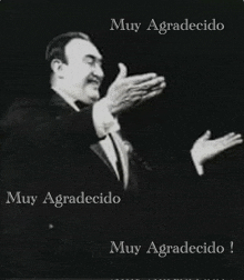 a man in a suit and tie is clapping his hands in spanish