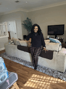 a woman in plaid pants stands in front of a large couch