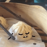 a dumpling with a face drawn on it is being eaten by a chopstick .