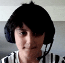 a young boy wearing headphones and a microphone is making a funny face .