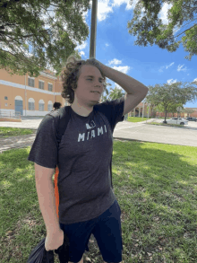 a man wearing a miami t-shirt holds his hand to his forehead