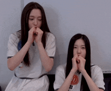 two girls are covering their noses with their hands and one has the letter h on her jersey