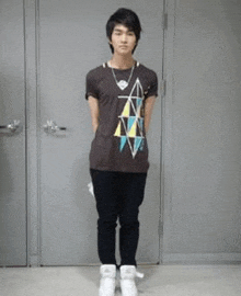 a young man is standing in front of a door wearing a t-shirt with triangles on it