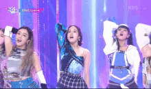 a group of girls are dancing on a stage and one of them is wearing a blue one shoulder top .