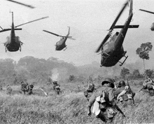 a black and white photo of soldiers in a field with helicopters flying overhead