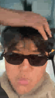 a pixelated image of a person wearing sunglasses and a hat