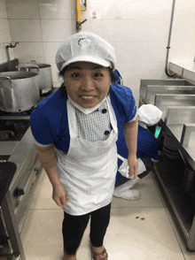 a woman in a kitchen wearing a white apron and a chef 's hat with the letter o on it