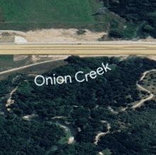 an aerial view of onion creek surrounded by trees and fields