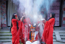 a group of women in red dresses are standing around a bride