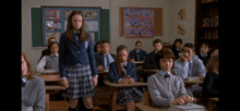 a girl in a school uniform stands in a classroom