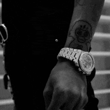 a black and white photo of a person wearing a watch and a tattoo on their arm