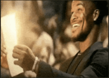 a man in a suit is smiling while holding a piece of paper in front of a crowd
