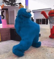 elmo and cookie monster are dancing together on stage