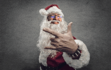 a man dressed as santa claus is making a rock sign