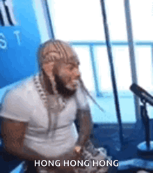 a man with dreadlocks is sitting in front of a microphone and saying hong hong hong .
