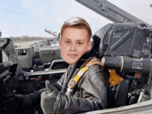 a young boy is sitting in the cockpit of a military vehicle