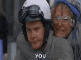 a man is carrying a woman on his back in a helmet and goggles .