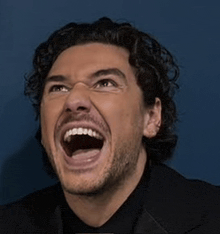 a man in a suit is laughing with his mouth wide open .