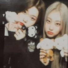 two girls are holding stuffed animals and posing for a picture together .