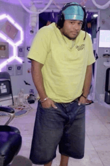 a man wearing headphones and a yellow shirt that says gallery dept on it