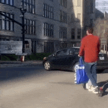 a man in a red shirt is walking down the street carrying a blue bag that says ' blue ' on it