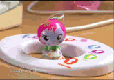 a doll is sitting on a toilet seat that says ' 2009 mattel inc. ' on the bottom