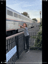 a boy pointing at a train with a sign that says do not enter until passengers have come to a complete stop