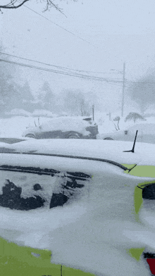 a yellow car is covered in snow in a snowy parking lot