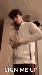a young man in a white jacket is standing in front of a door and says `` sign me up '' .