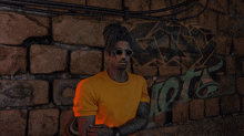 a man wearing sunglasses and a yellow shirt stands in front of a brick wall that has graffiti on it that says shots