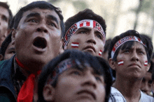 a group of men wearing headbands with the word peru on them are watching a sports game .