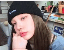 a young woman wearing a black beanie is sitting on a couch .