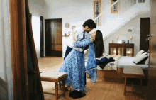 a man and woman are kissing in a bedroom with stairs in the background