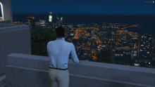 a man in a white shirt stands on a balcony overlooking a city