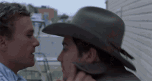 a man in a cowboy hat kisses another man