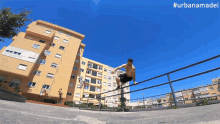 a man is doing a handstand on a railing in front of a building with #urbanamadei written on the bottom