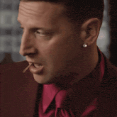 a man in a red suit and pink tie looks at the camera