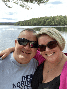 a man wearing sunglasses and a shirt that says the north face poses with a woman