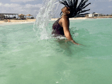 a woman in a bathing suit is splashing in the ocean